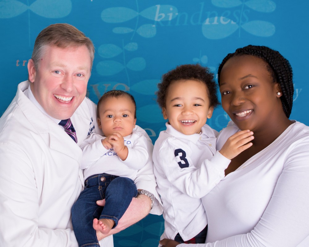 Uconn Fertility success story image of young boy with mother posing with reproductive endocrinologist David Schmidt holding young baby