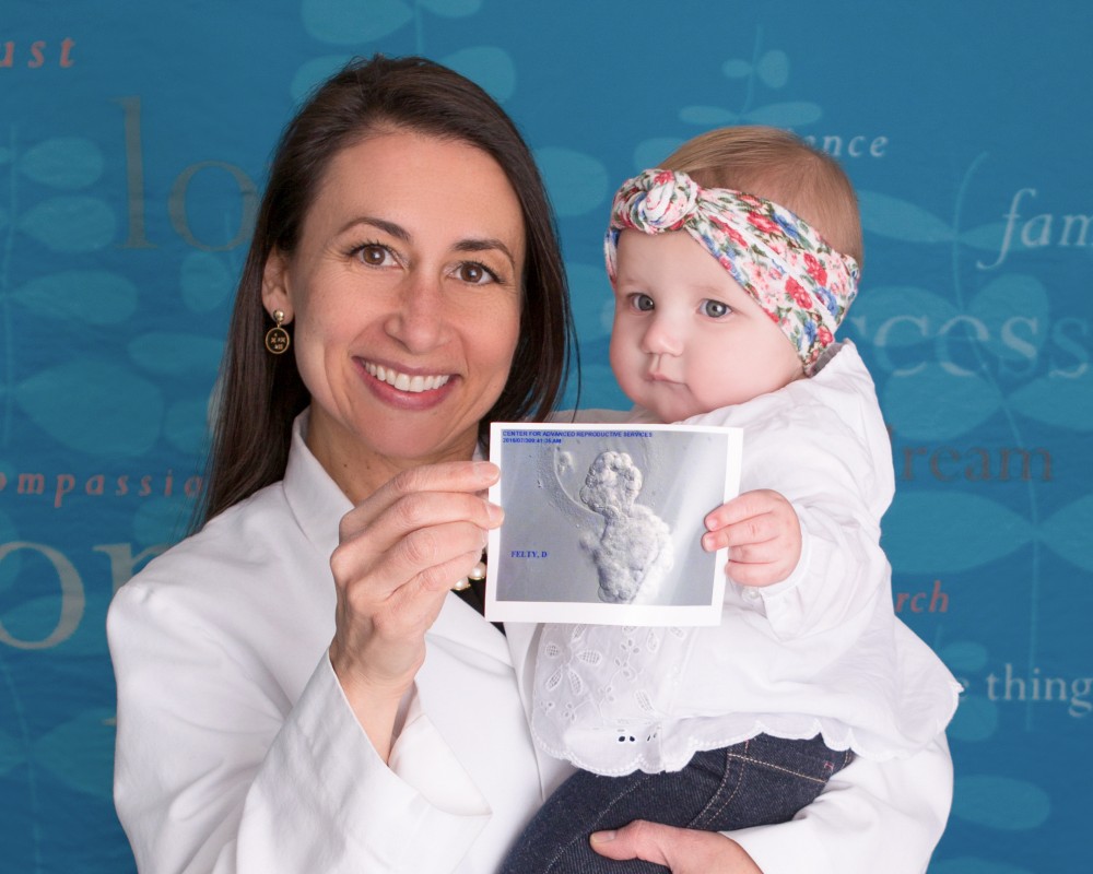 Uconn Fertility success story image of baby posing with reproductive endocrinologist Andrea J. DiLuigi and holding image from embryologist