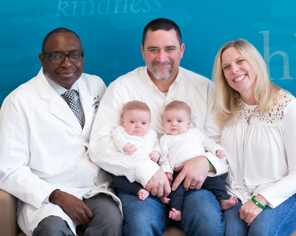 Uconn Fertility success story image of baby twins held by new parents posing with reproductive endocrinologist Lawrence Engmann